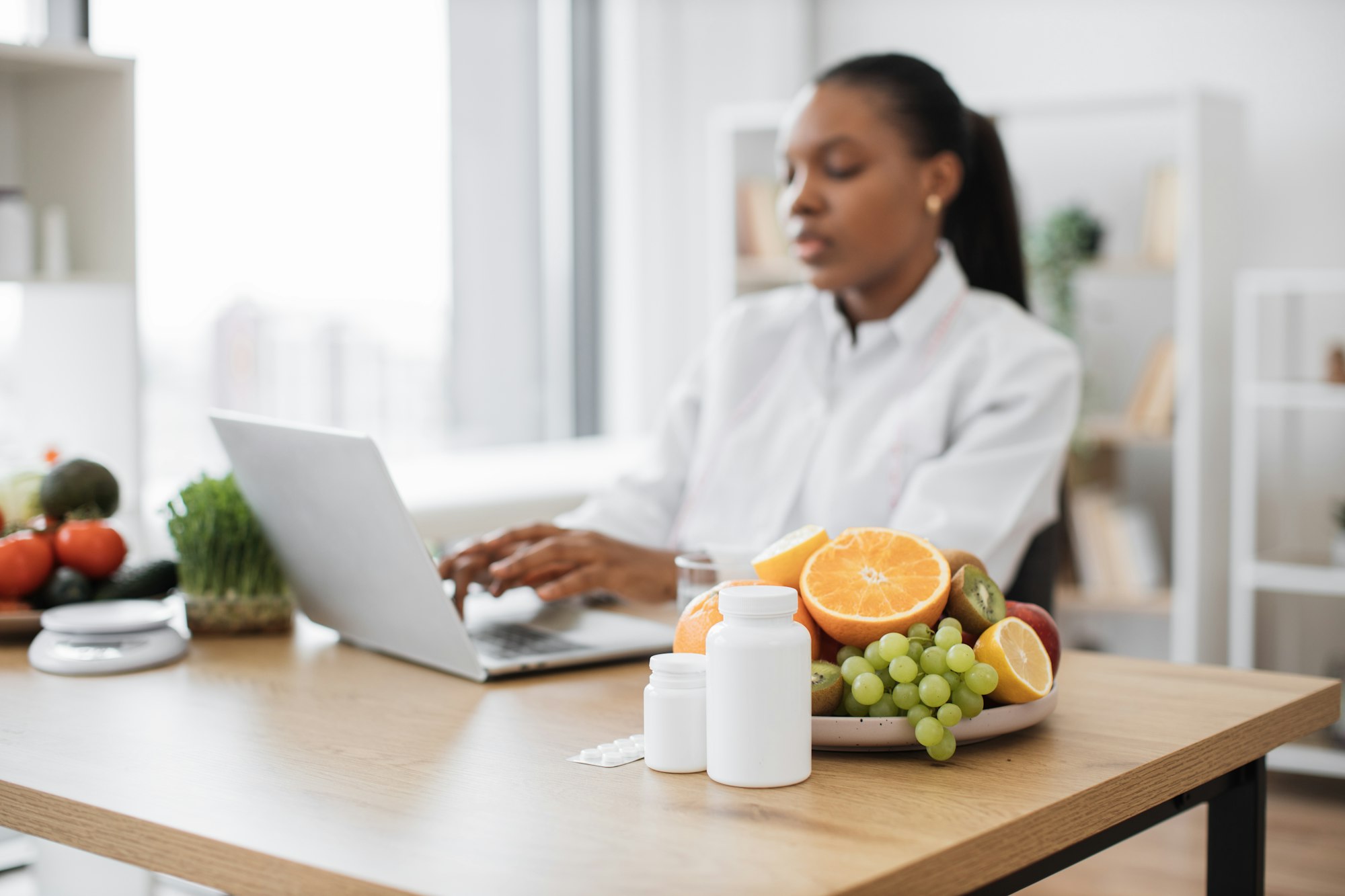 Fruits and medicine being placed on desk at nutritionist's